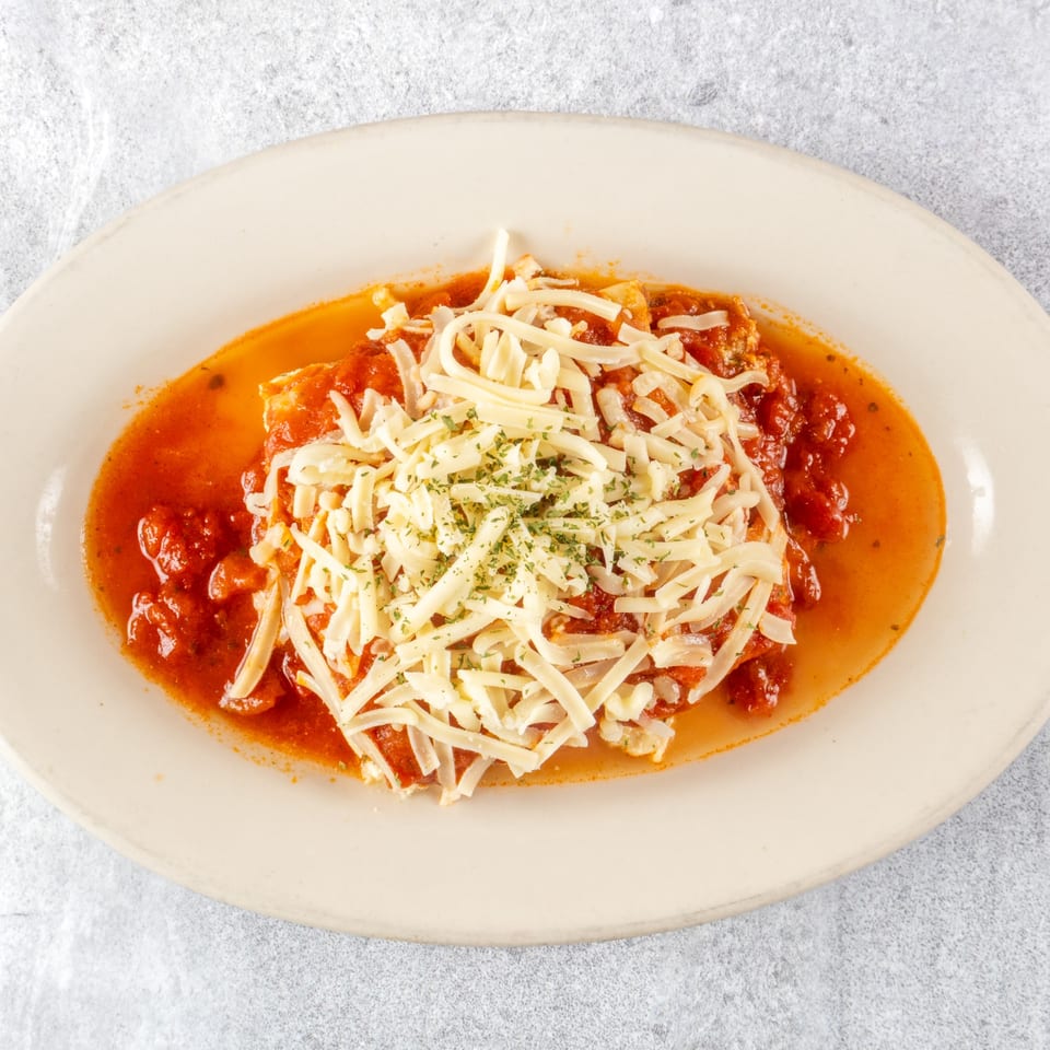 Zoe's Pizza and Seafood's chicken parmesan, topped with shredded cheese and parsley in a red sauce.