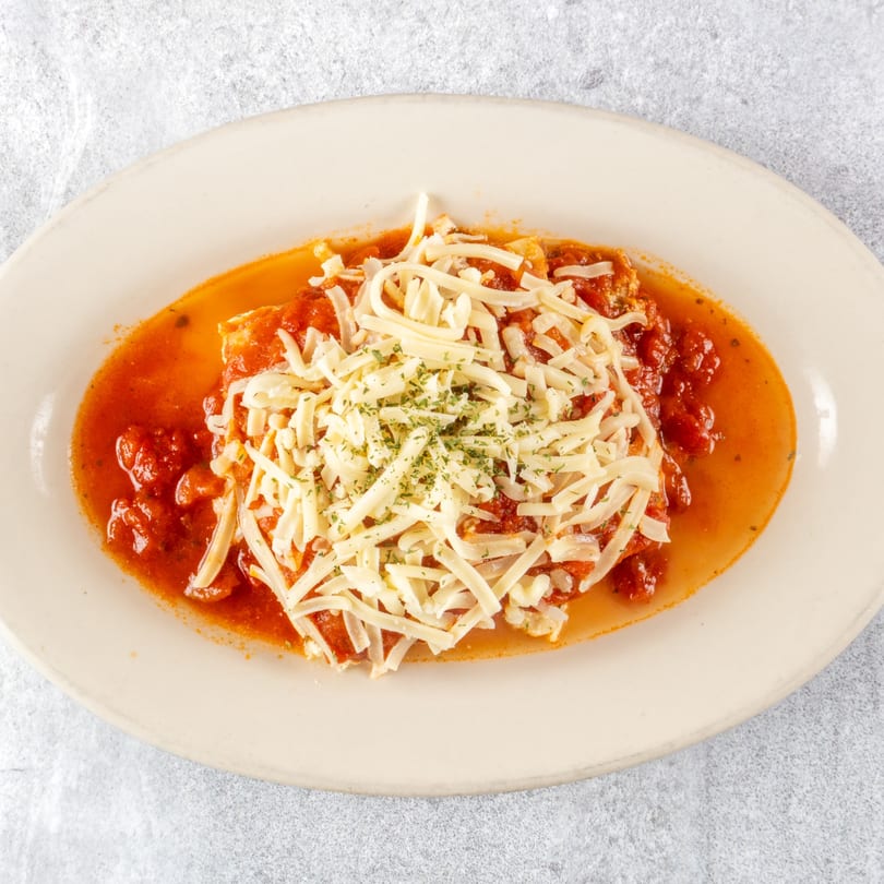 Zoe's Pizza and Seafood's chicken parmesan, topped with shredded cheese and parsley in a red sauce.