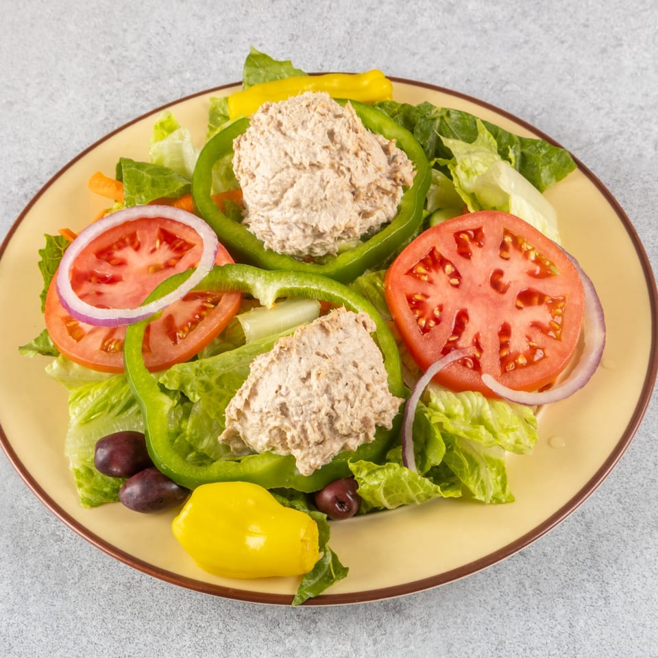 Tuna salad on a bed of lettuce with tomatoes, onions, green peppers, olives, and a banana pepper.