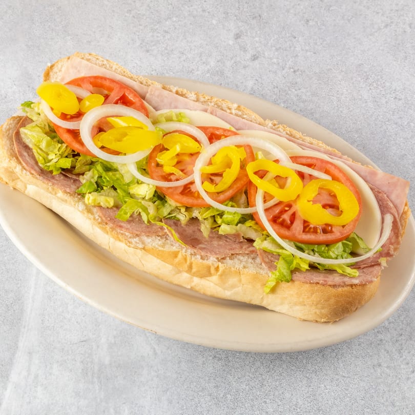 A large Zoe's Pizza and Seafood sub sandwich, overflowing with meats, cheese, lettuce, tomatoes, onions, and peppers.